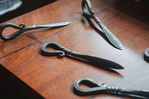 Hand forged shellfish knives on wooden surface showcasing craftsmanship.