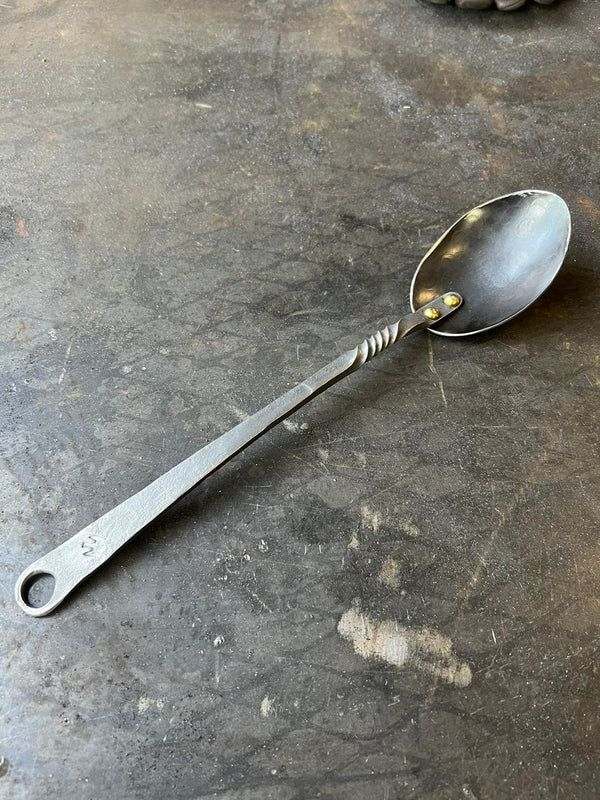 Hand forged stainless steel spoon with brass rivets, 13.5 inches long.