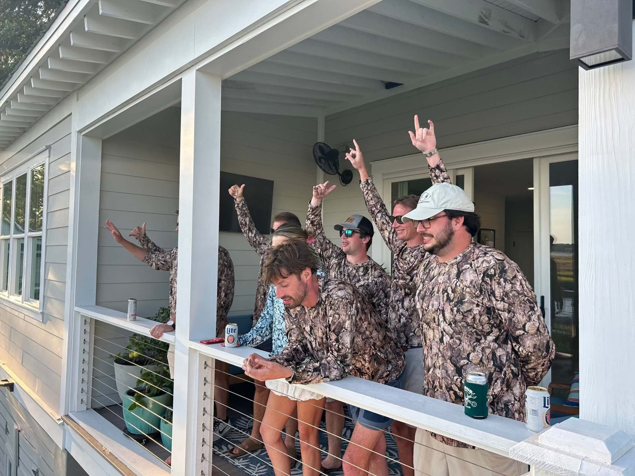 Group of men wearing Oystaflage Long Sleeve camo performance shirts on porch during daytime