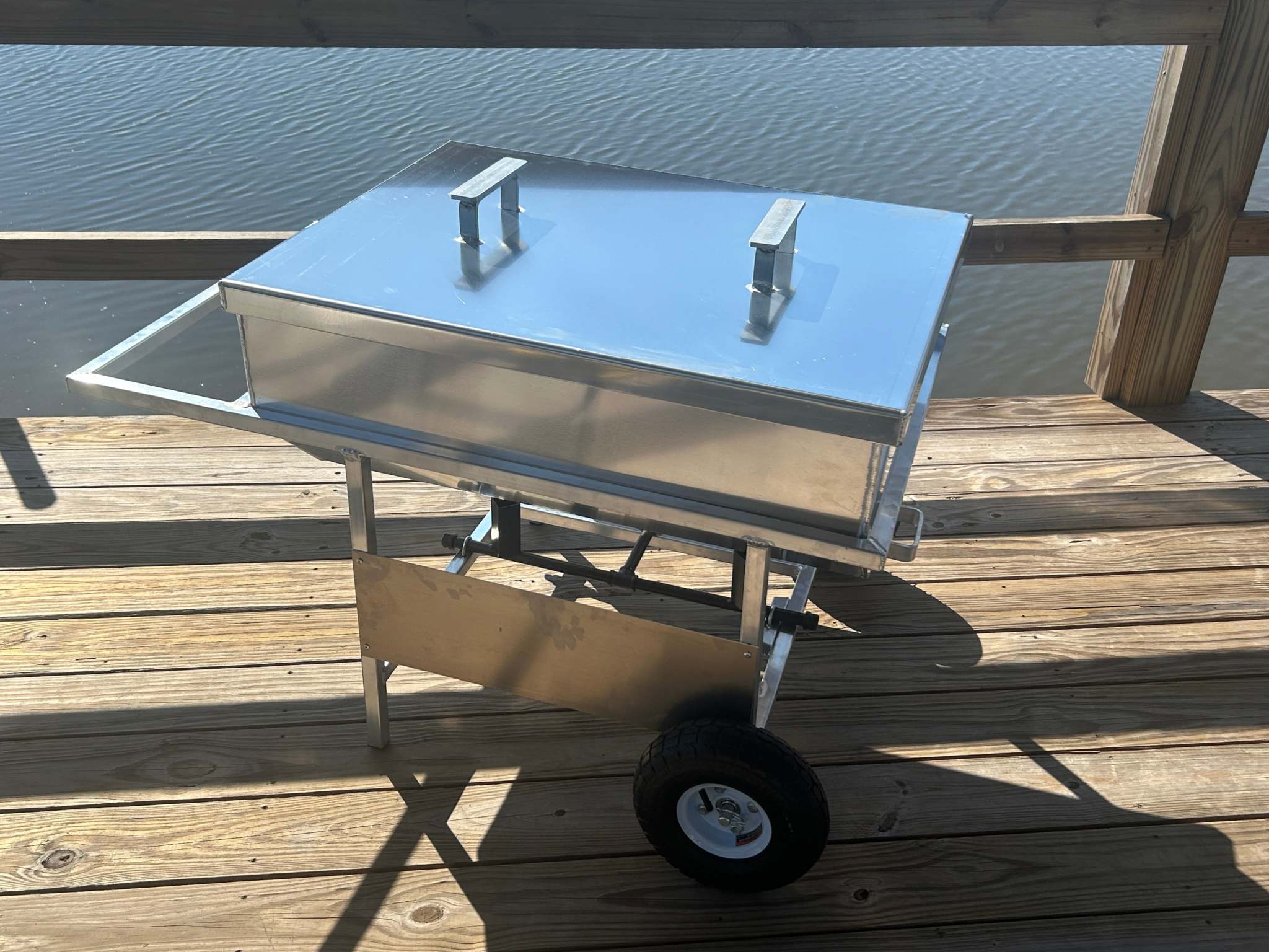 Wheeled aluminum cooker with double baskets on a wooden deck, perfect for seafood boiling.