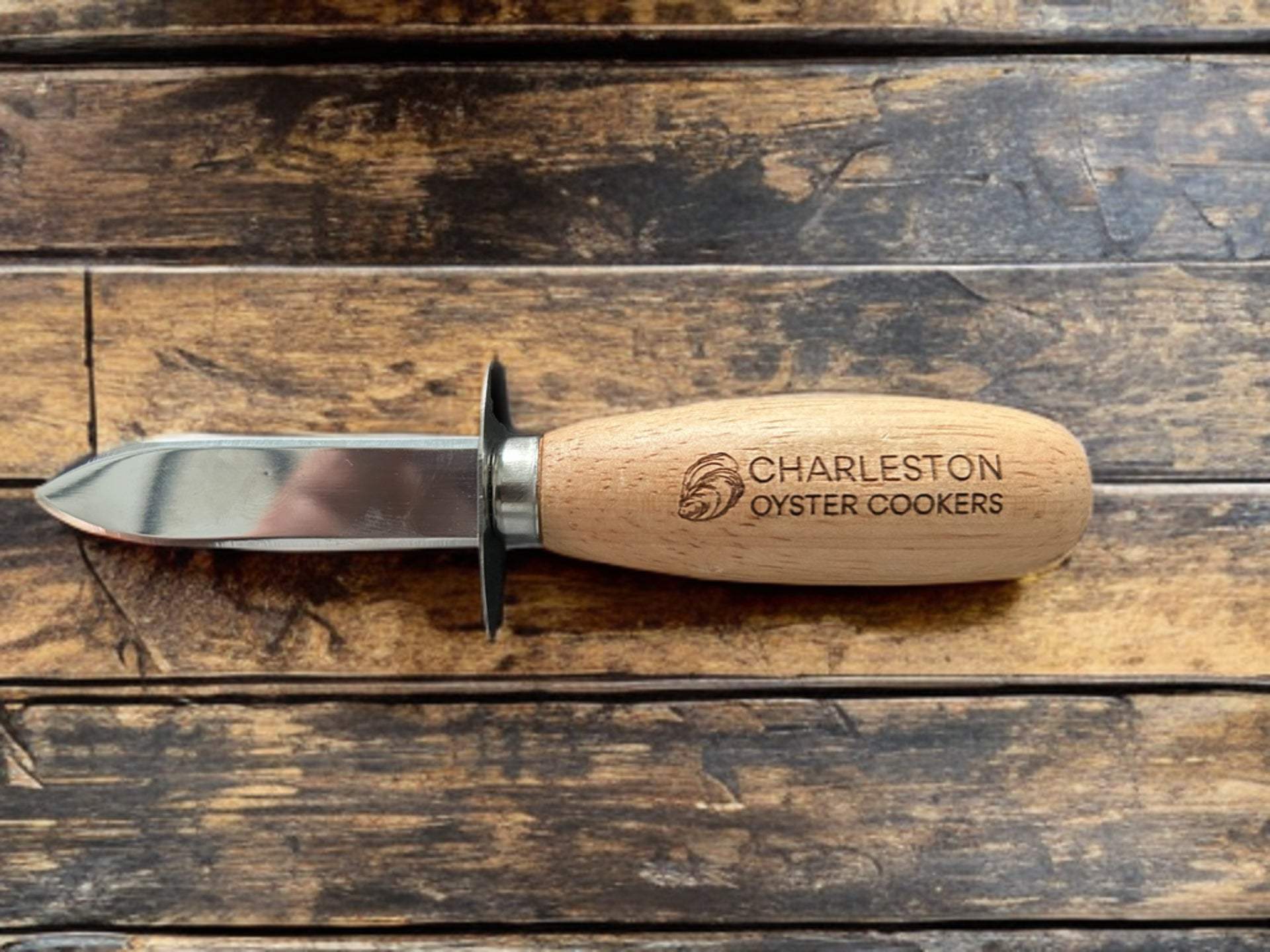 Wood Handle Oyster & Shellfish Knife with engraved Charleston Oyster Cookers logo on ergonomic wooden handle and stainless steel blade on rustic wooden surface